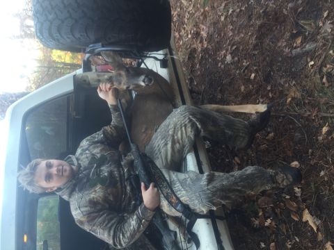 1974 Ford Bronco - A hunter poses with a deer in the bed of a white pickup truck, with a spare tire mounted above.