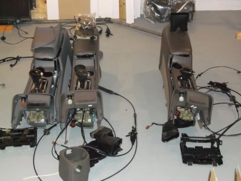 1999 Mercury Grand Marquis - Three car consoles with shifters and associated wiring are laid out on a floor, likely for sale or repair.