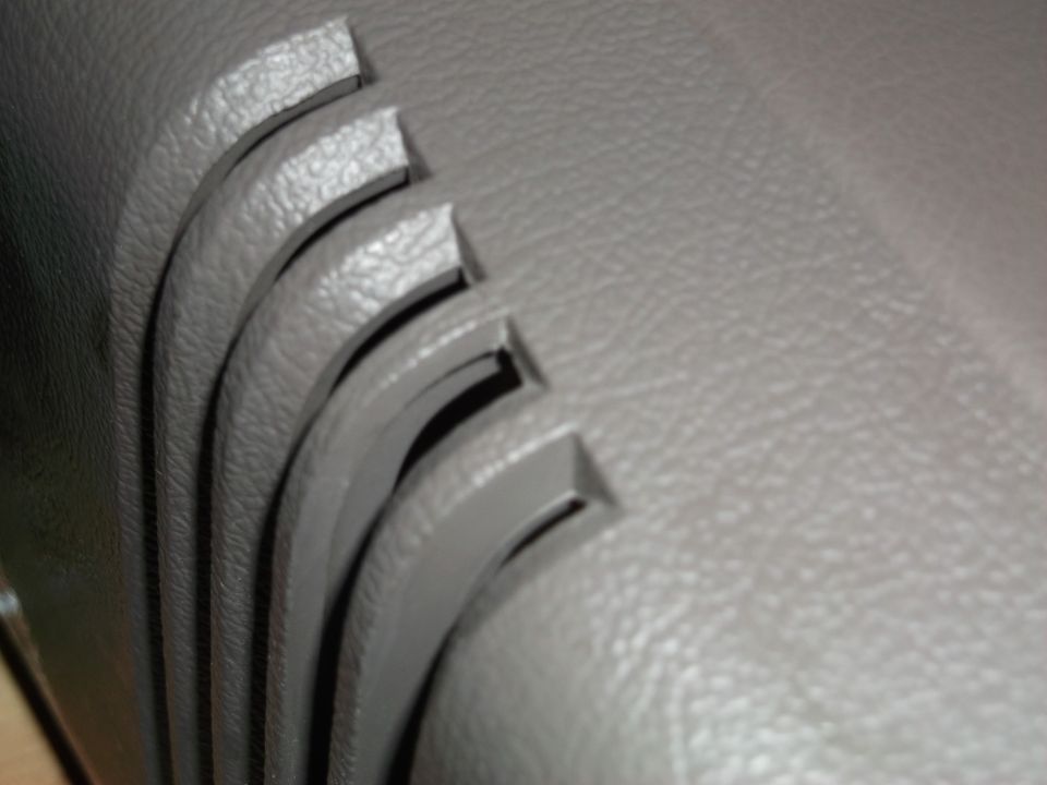 close-up of gray textured plastic trim with curved slots inside a car