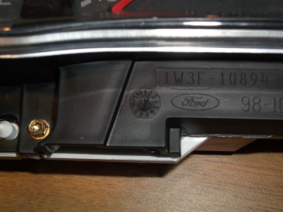 Close-up of a black dashboard part with Ford logo and part numbers.