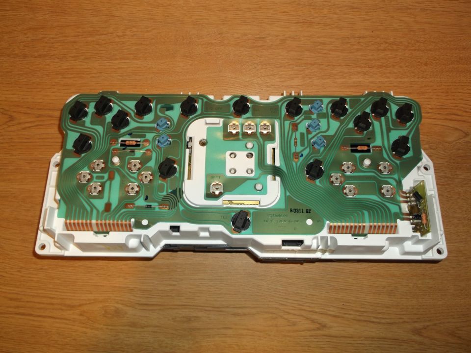 Back of a circuit board with electrical components, mounted on a white housing.