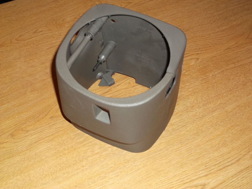 Tan plastic steering column shroud on wooden surface