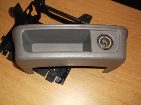 1999 Mercury Grand Marquis - A gray plastic console with a cigarette lighter socket is shown, mounted on a black metal bracket. The console has an open storage compartm…