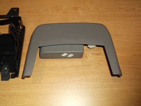 1999 Mercury Grand Marquis - A gray plastic console trim piece with a small gray box attached underneath is shown on a wooden surface. To the left is a black metal brac…