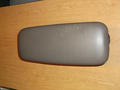 1999 Mercury Grand Marquis - A grey, padded armrest lid with visible scuff marks and scratches is shown from a top-down perspective, resting on a wooden surface.