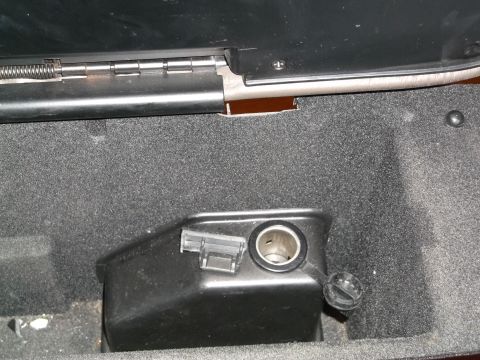 1999 Mercury Grand Marquis - A close-up view of a car's interior shows a black plastic housing with a 12V power outlet and a hinged cap. The outlet is located within a…