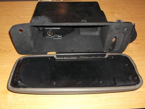 1999 Mercury Grand Marquis - An open glove box compartment with a 12V power outlet visible inside. The compartment is lined with black fabric and sits on a wooden surfa…