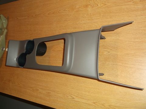 1999 Mercury Grand Marquis - A gray plastic center console trim piece with two cup holders and a rectangular opening is shown on a wooden surface.