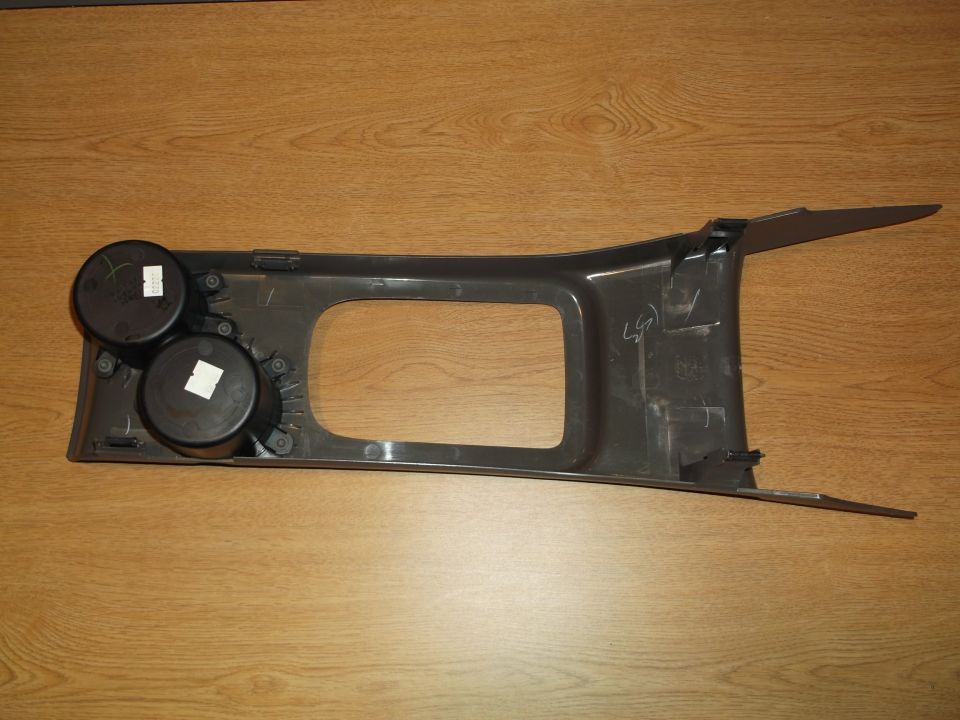 Dark gray plastic center console trim with two cup holders and a rectangular cutout.