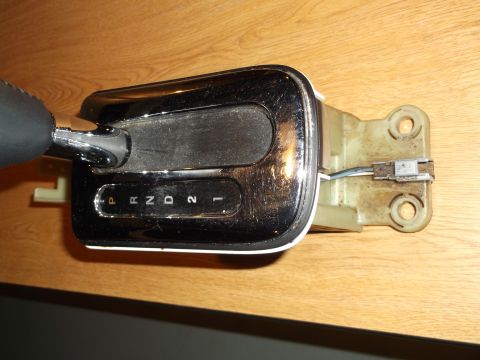 1999 Mercury Grand Marquis - A close-up, overhead view of a car's automatic transmission shifter assembly. The shifter has a chrome trim and displays the gear selection…