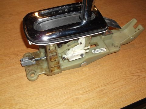 1999 Mercury Grand Marquis - This is a close-up, slightly angled view of a disassembled automatic transmission shifter assembly, likely from a car. The assembly include…