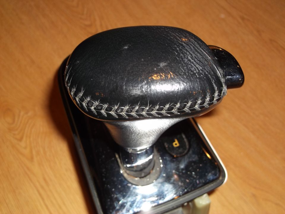 Black leather gear shifter knob with white stitching and a "P" indicator.