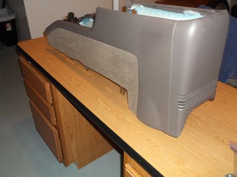 1999 Mercury Grand Marquis - A gray plastic center console with a fabric insert sits on a wooden desk. The console appears to be from a vehicle, possibly a Mercury Gran…