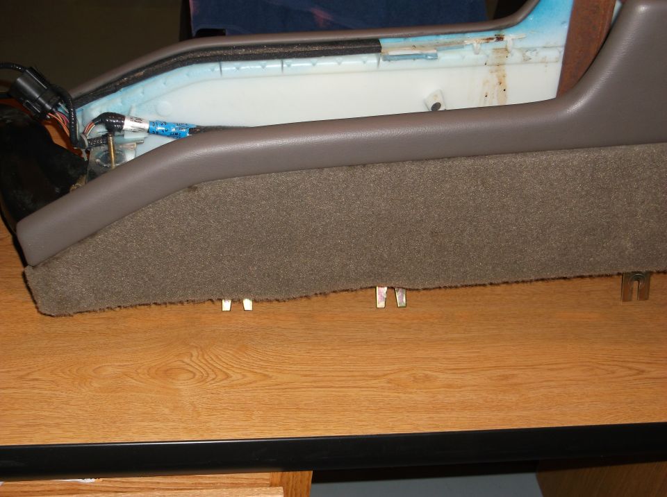Side view of a car's center console with brown carpet and grey trim.