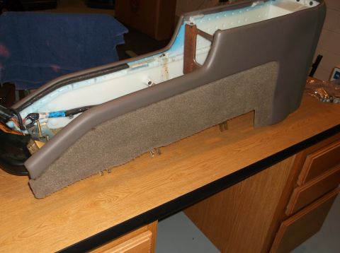1999 Mercury Grand Marquis - A disassembled car center console, possibly from a 1999 Mercury Grand Marquis, is shown resting on a wooden desk. The console features brow…