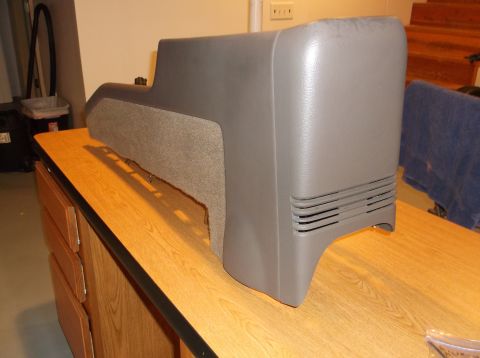 1999 Mercury Grand Marquis - A gray plastic automotive center console with a textured gray fabric insert sits on a wooden desk.