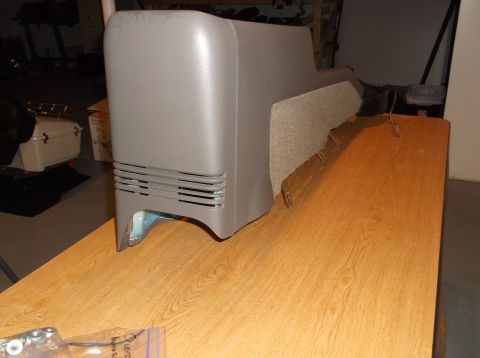 1999 Mercury Grand Marquis - A grey plastic automotive center console or storage unit with horizontal vents is placed on a wooden table. A fuzzy, beige upholstered sect…