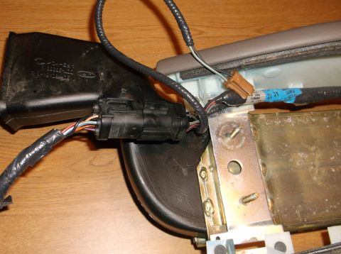1999 Mercury Grand Marquis - A close-up view shows a black plastic electrical connector with multiple colored wires attached to a metal bracket and black plastic housin…