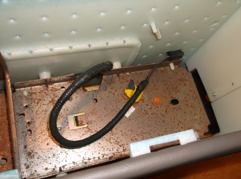 1999 Mercury Grand Marquis - A close-up view shows a rusty metal frame with black wiring harnesses and connectors, likely from the interior of a vehicle. The frame is p…