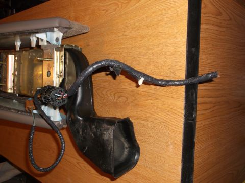1999 Mercury Grand Marquis - A close-up view shows a black plastic duct and a bundle of black-wrapped wires with a multi-pin connector attached to a metal bracket. The…