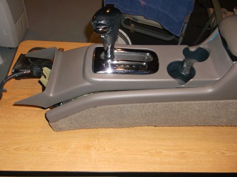 1999 Mercury Grand Marquis - A close-up view of a car's center console, featuring a gear shifter and cup holders. The console is made of brown plastic and is resting on…
