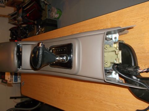 1999 Mercury Grand Marquis - A close-up view of a car's center console with a gear shifter and part of the dashboard removed, revealing internal components and wiring.