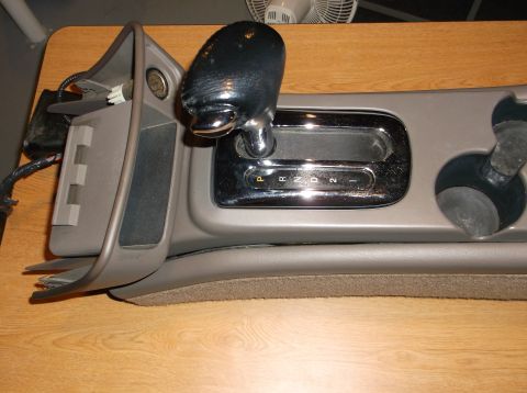 1999 Mercury Grand Marquis - This is a close-up of a car's automatic transmission shifter assembly, including the shifter handle, gear indicator display, and a cup hold…
