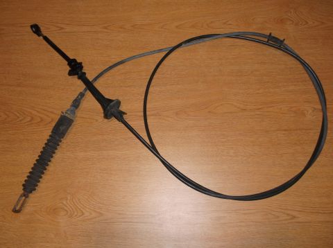1999 Mercury Grand Marquis - A black throttle cable assembly with a rubber boot and a gray outer sheath is laid out on a wooden surface.