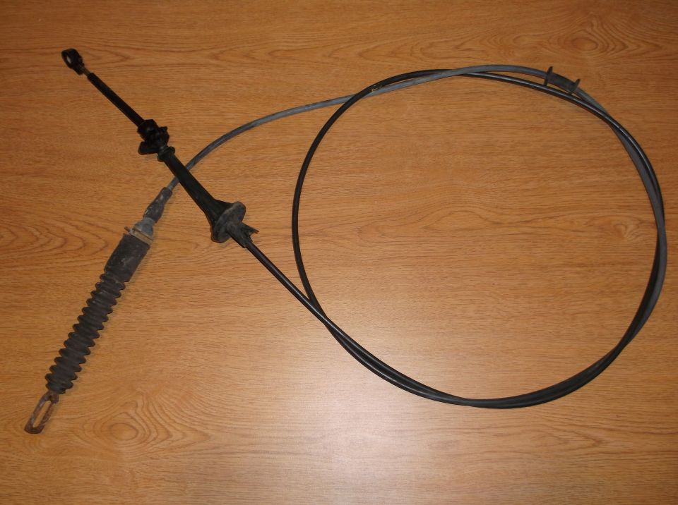 Black throttle cable assembly with rubber boot and gray sheath on wood