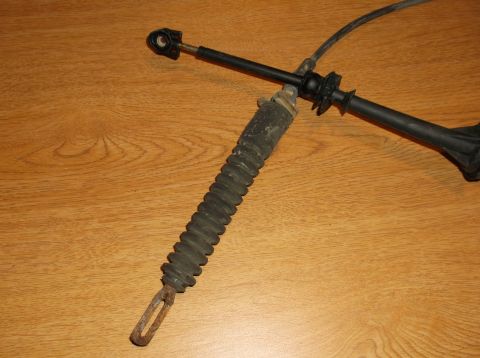 1999 Mercury Grand Marquis - A black and metal cable assembly with a corrugated rubber boot is shown against a wooden background. The assembly appears to be a part from…