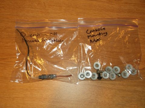 1999 Mercury Grand Marquis - Two clear plastic bags are laid out on a wooden surface. The left bag contains a wire harness labeled "Overdrive Off Harness into Console".…