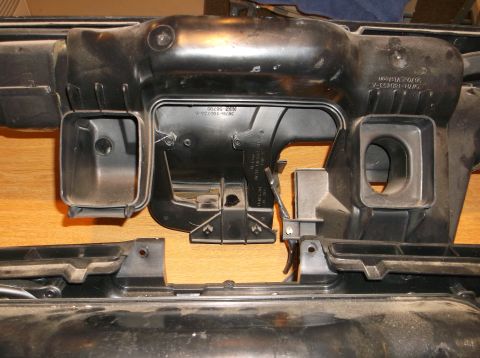 1999 Mercury Grand Marquis - A black plastic automotive part, likely an air intake or ducting component, is shown against a wooden background. The part has several open…