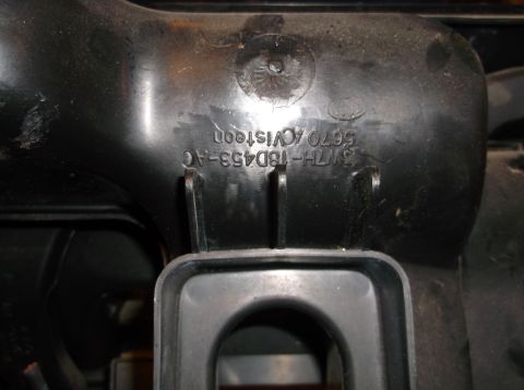 1999 Mercury Grand Marquis - A close-up view of a black plastic part with embossed text that reads "3W7H-18D453-AC 5670 ACV15ton" and a Ford logo. The part is dusty and…