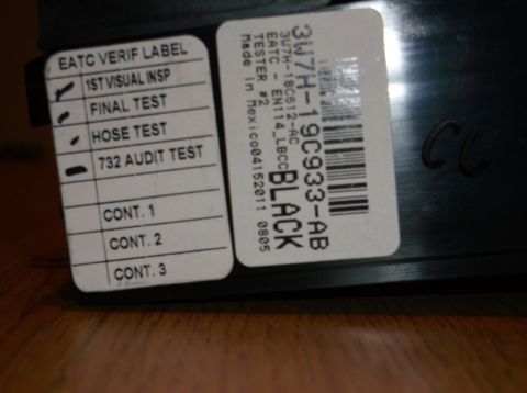 1999 Mercury Grand Marquis - A close-up of two labels on a black automotive part. The left label lists inspection and test results, with checkmarks next to '1ST VISUAL…