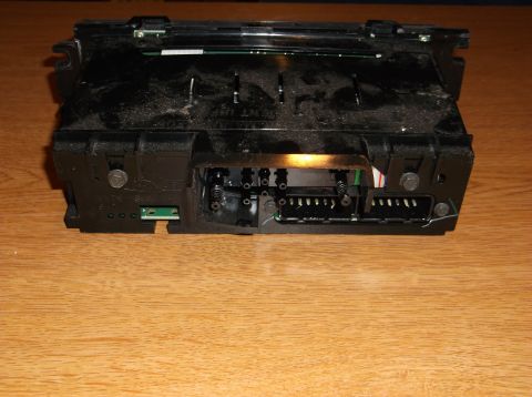 1999 Mercury Grand Marquis - A close-up, angled view of the internal components of a black electronic module, likely from a vehicle's dashboard, resting on a wooden sur…