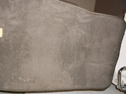 1999 Mercury Grand Marquis - A close-up view of a dark gray floor mat with the letters "LSE" embossed on the lower left corner. The mat appears to be for a vehicle.