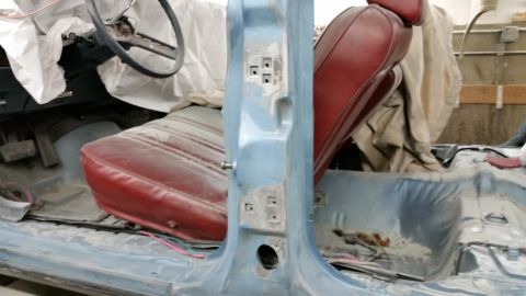 2001 Ford Crown Victoria - Photograph of a car interior during restoration showing a red seat and primered body shell, not a technical document.