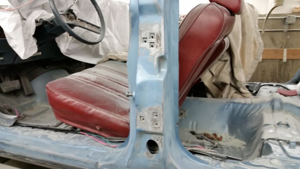 Photo of a car interior with red bucket seat and bare blue body shell during restoration