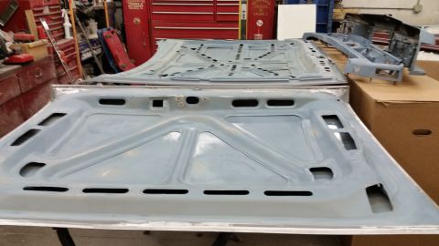 2001 Ford Crown Victoria - Photograph of primered automotive floor pan panels in a shop, not a technical document.