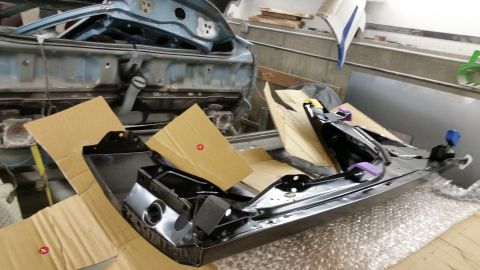 2001 Ford Crown Victoria - Photograph of painted automotive body parts on cardboard in a shop, not a technical document.