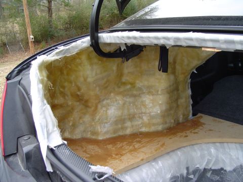 1999 Ford Taurus - Open trunk of a dark sedan lined with resin-soaked fiberglass matting over the rear seat-back wall, with masking paper taped around the edg…