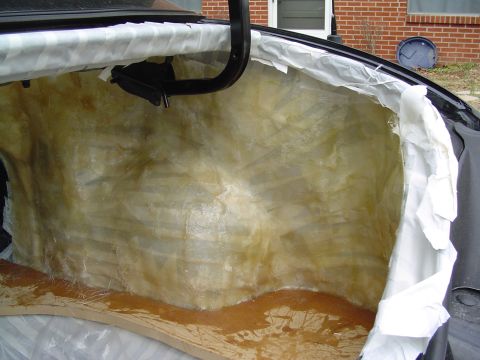 1999 Ford Taurus - Open sedan trunk with the rear seat bulkhead covered in cured amber fiberglass resin and cloth, masked off with white plastic sheeting and…