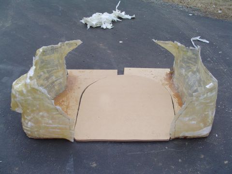 1999 Ford Taurus - Custom fiberglass trunk enclosure under construction, sitting on asphalt: an MDF base board with a curved cutout flanked by two hand-laid f…