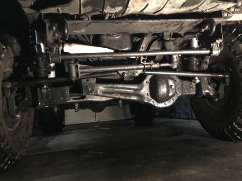 1993 Ford Bronco - The underside of a vehicle, likely a 1993 Ford Bronco, showing the front axle, steering components, and suspension system. The vehicle appe…