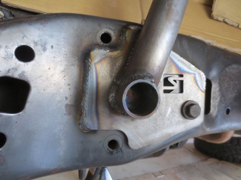 1996 Ford Bronco - A close-up view shows a heavily modified metal frame with visible welds and a bolted-on bracket. A cylindrical tube is welded to the frame,…