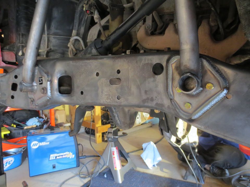 Modified 1996 Ford Bronco frame with custom welds and reinforcement brackets, Miller welder in foreground.