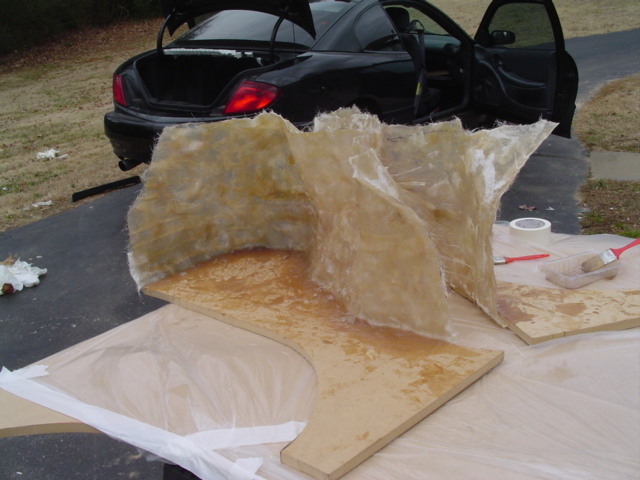 Fiberglass layup over a plywood form for a custom enclosure behind a black coupe