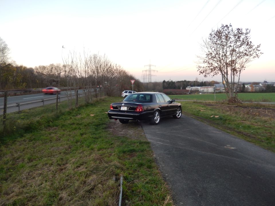 Black Mercury sedan parked on the side of a road.