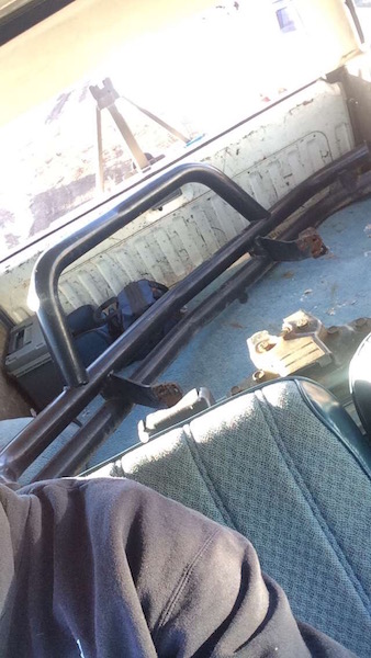 1981 Ford Bronco - The interior of a vehicle, likely a truck or SUV, shows a roll cage and other metal components loaded in the cargo area. A car jack is visi…