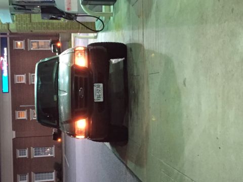 1991 Ford Bronco - A dark colored Ford van is parked at a gas station at night. The vehicle's headlights and turn signals are illuminated, and a Virginia lice…